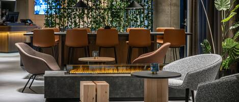 A modern bar area with seating, a fire feature, and a television in the background.