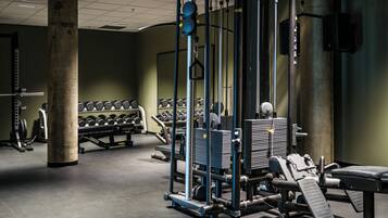 A gym with weightlifting equipment, dumbbells, and a squat rack.