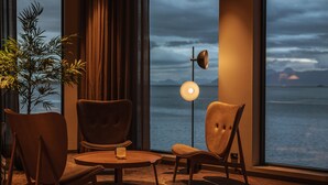 A room with a large window, a floor lamp, and two chairs around a small table. - Quality Hotel Harstad (Harstad)