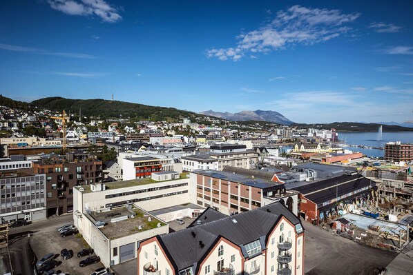 A coastal town with a mix of residential and commercial buildings, a prominent church, and a clear view of the sea and mountains in the background. - Quality Hotel Harstad (Harstad)
