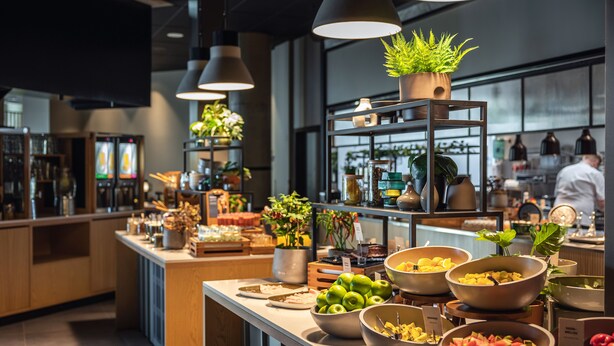A buffet area with various food bowls, potted plants, and a modern kitchen in the background. - Quality Hotel Harstad (Harstad)