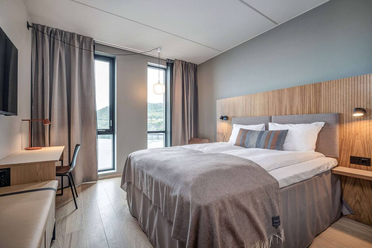 Una habitación de hotel moderna con una cama grande, un escritorio y una silla.