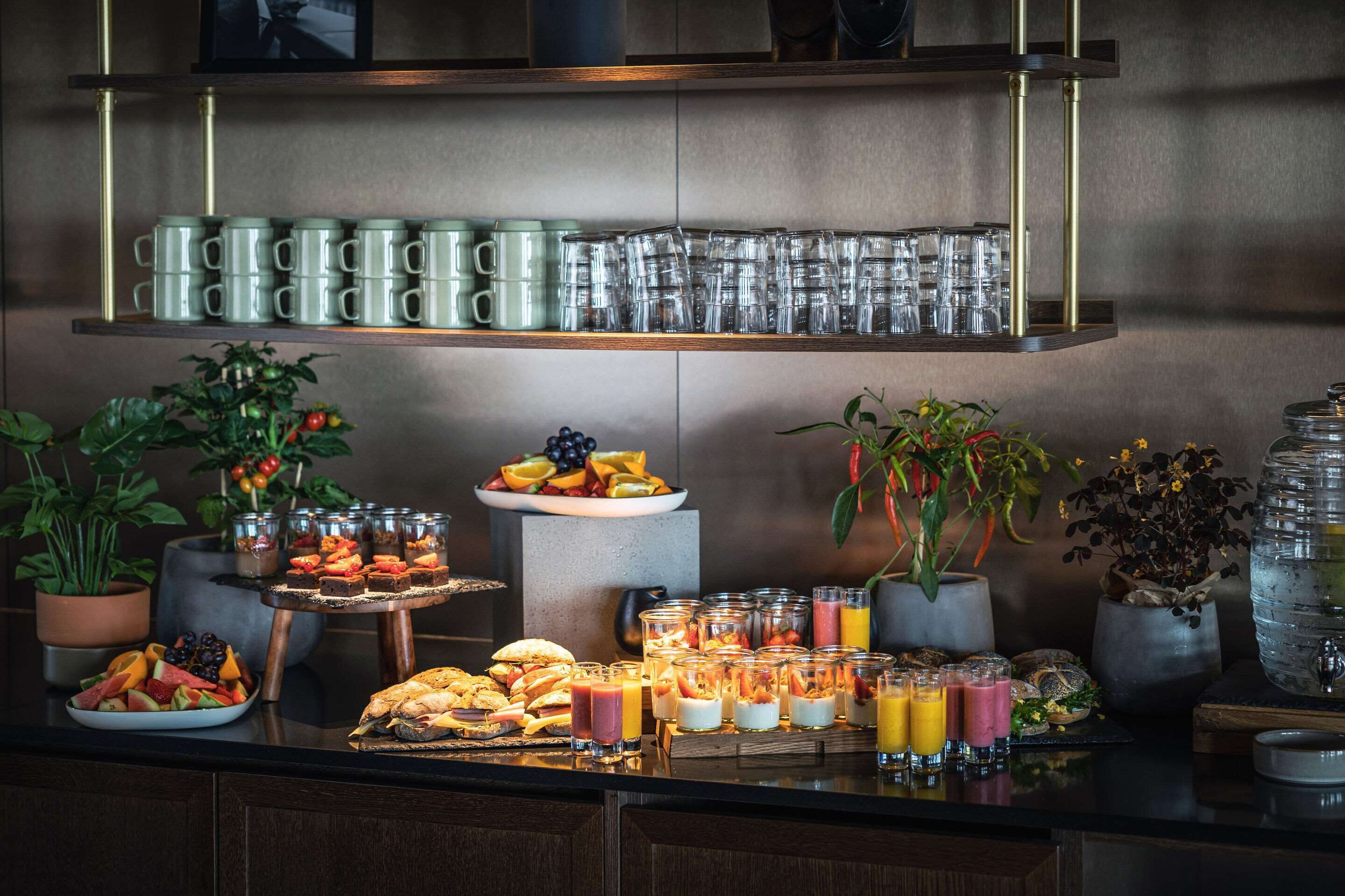 Un bufé de desayuno con diversos alimentos y bebidas, incluyendo frutas, pasteles y jugos.