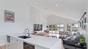 Een moderne keuken met een centraal eiland, een zithoek met een bank en stoelen, en een groot raam met uitzicht op de omgeving.