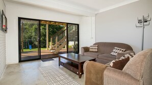 Een moderne woonkamer met een bank, salontafel en een schuifdeur naar een terras.