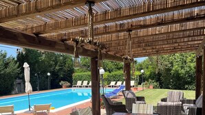 En udendørs terrasse med swimmingpool, tr æborde og stole.