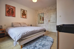 A bedroom with a bed, a fluffy rug, a dresser, and a mirror on the wall.