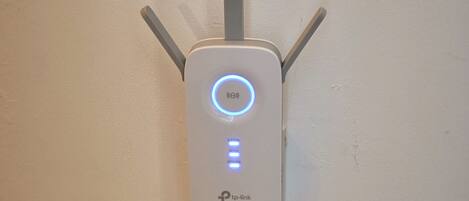 A wall-mounted device with a circular blue light and two vertical antennas.