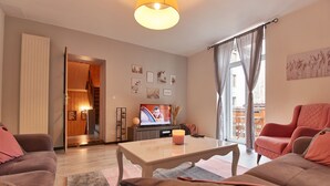 Een moderne woonkamer met een bank, een salontafel en een televisie. Er is een trap die naar een verdieping leidt.