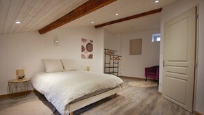 Een slaapkamer met een bed, nachtkastje, stoel en deur.