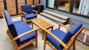 Un espacio al aire libre con mobiliario de madera y cojines azules.