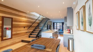 Una cocina moderna con paneles de madera, una escalera y un comedor con mesa de madera.