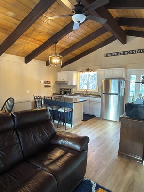 A spacious living area with a leather sofa, a dining table with chairs, a kitchen with modern appliances, and a ceiling fan. - Bartlett Condo close to Storyland and Jackson (Bartlett)