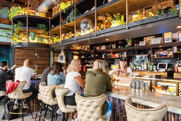 Enjoy a drink at the bar, surrounded by a unique display of bottles, decorative objects, and plants.