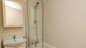 A bathroom with a glass-enclosed shower, a sink, and a cabinet. - The Bobbin, Number 11 (Carnforth)