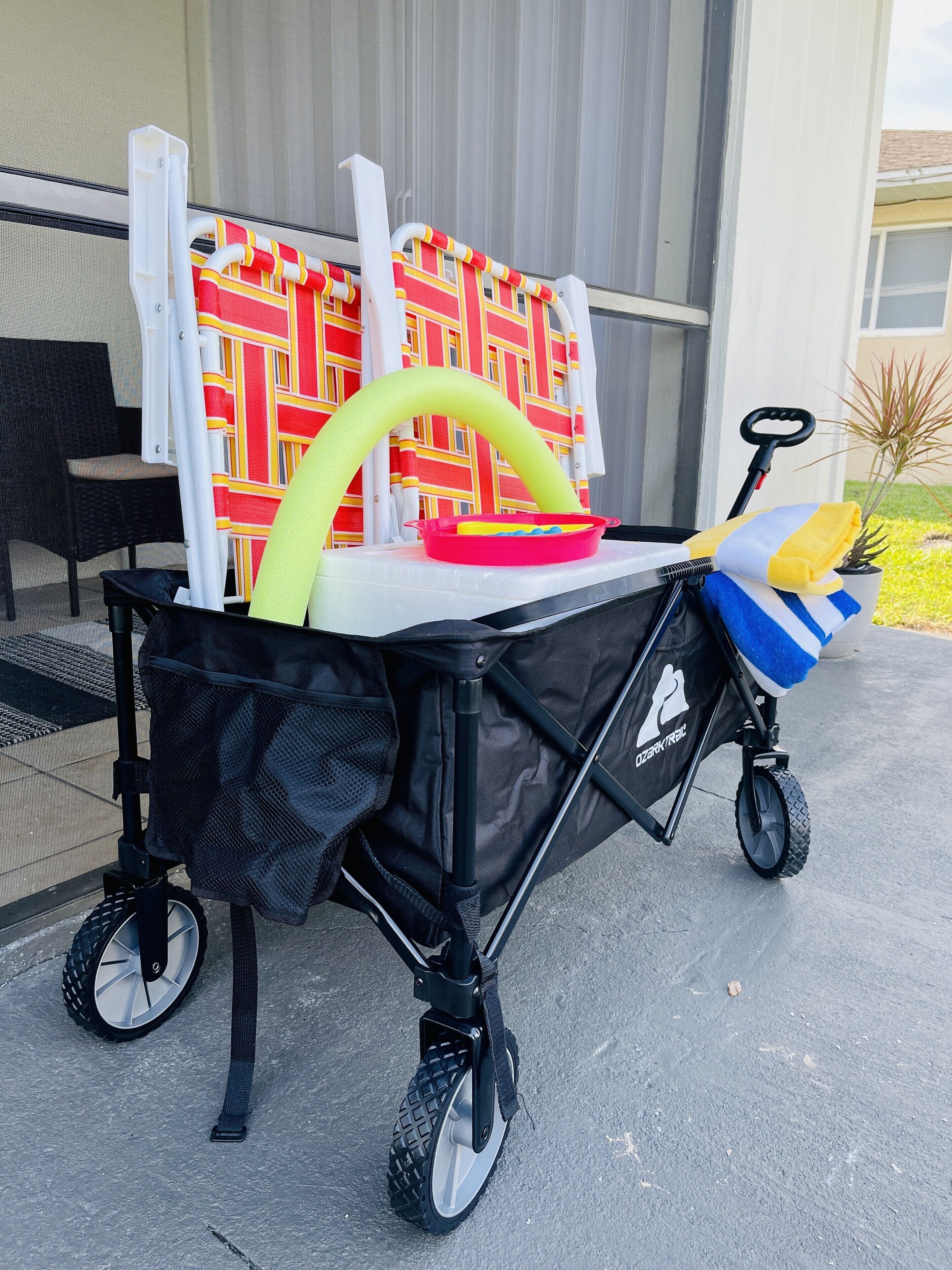 Un carrito de bebé con estructura negra y una bolsa de malla para guardar objetos.