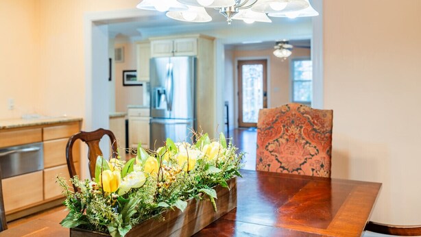 Un comedor con una mesa de madera, un centro de mesa floral y una silla estampada.