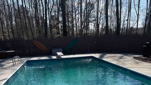 Una piscina rectangular con una escalera metálica en un lateral, rodeada por una plataforma de concreto.