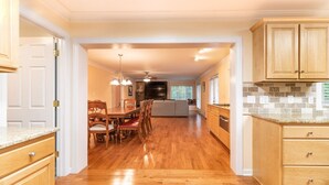 Una cocina amplia con armarios de madera, una zona de comedor con sillas y una isla central.