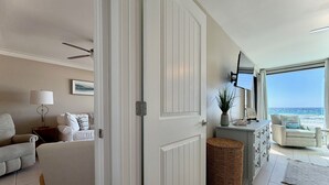 Een woonkamer met uitzicht op de oceaan, een bank, een lamp en een televisie.
