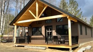 A wooden cabin with a gabled roof, a porch with railings, and a number '8' on the side. - New Cabin in Eustis.Mtn, River & Dam Views (Eustis)