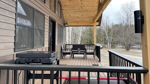 A wooden deck with a barbecue grill, two chairs, and a table. - New Cabin in Eustis.Mtn, River & Dam Views (Eustis)