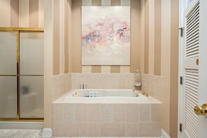 Un bagno con una vasca freestanding, un box doccia in vetro e un grande quadro astratto appeso alla parete.