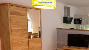 Una sala moderna con un armario de madera, un televisor sobre un mueble de madera y una pequeña mesa.