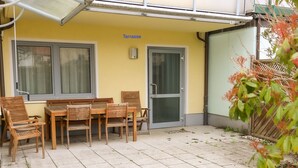 Una terraza exterior con una mesa y sillas, una puerta y una ventana.