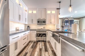 Une cuisine moderne avec des armoires blanches, des appareils en acier inoxydable et un plancher en bois.