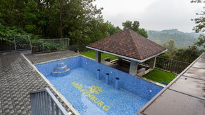 A swimming pool with a blue tiled floor and a roofed pavilion. - Ramee Wolkenburg Resort and Spa Munnar (Devikolam)