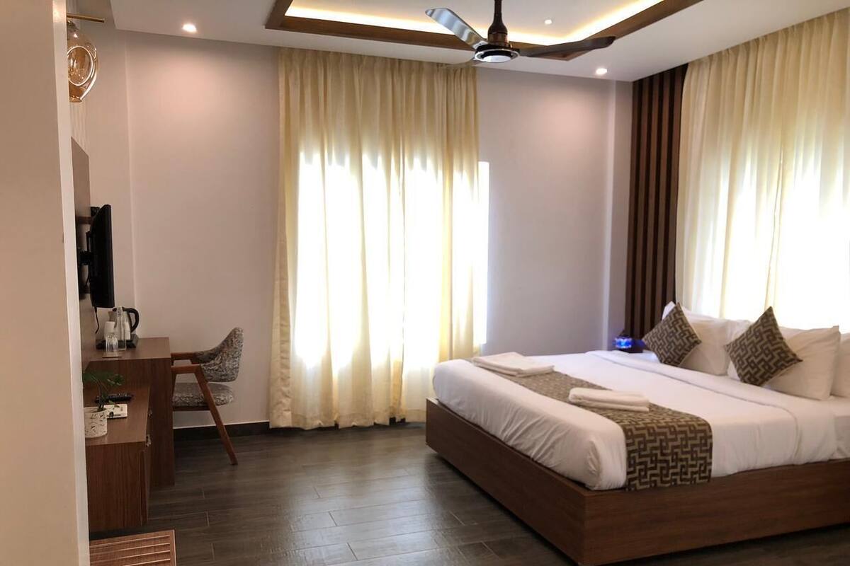 Quarto de hotel moderno com uma cama grande, uma escrivaninha e um ventilador de teto.