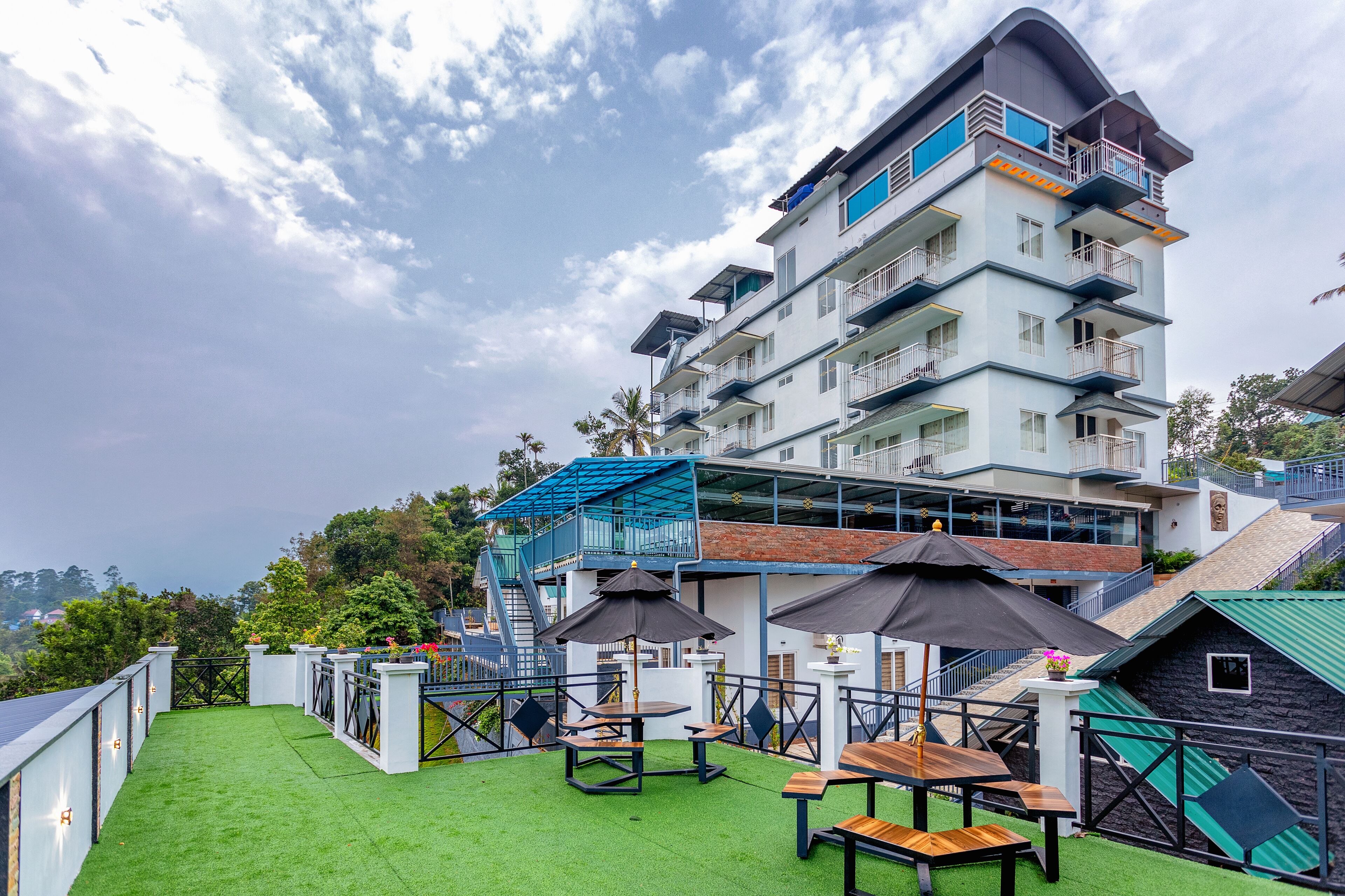 A rooftop terrace with artificial grass, outdoor tables, and umbrellas.
