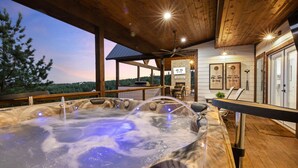 Un bain à remous doté d’une terrasse en bois et d’un mur en pierre sur lequel est apposée une enseigne indiquant « Eye Candy ».
