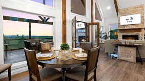 Un coin repas offrant une vue sur le paysage, une cheminée et une pancarte sur laquelle on peut lire : « Bienvenue au PORCH ».