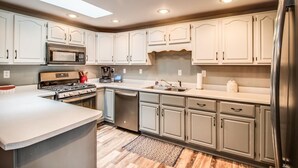 Una cucina moderna con mobili bianchi, elettrodomestici in acciaio inossidabile e un lucernario.