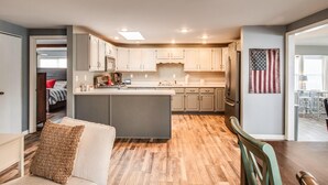 Una cucina moderna con isola centrale, pavimento in legno e mobili chiari.