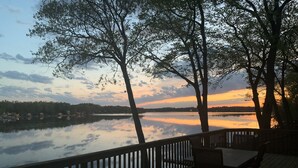 Un pontile di legno con vista su un lago tranquillo e alberi che si riflettono nel cielo.