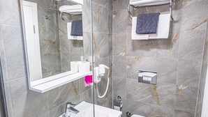 Un baño moderno con cabina de ducha de vidrio, un lavamanos blanco y un inodoro.