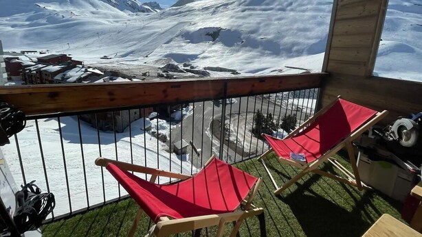 A balcony with two red chairs, a wooden table, and a view of a snowy mountain landscape. - Magnificent apartment with stunning views❤️Schuss⛷ (Tignes)
