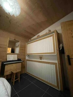 A wooden room with a desk, chair, and a large mirror.