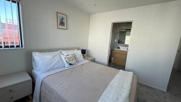 Un dormitorio con cama, mesita de noche, cómoda y ventana.