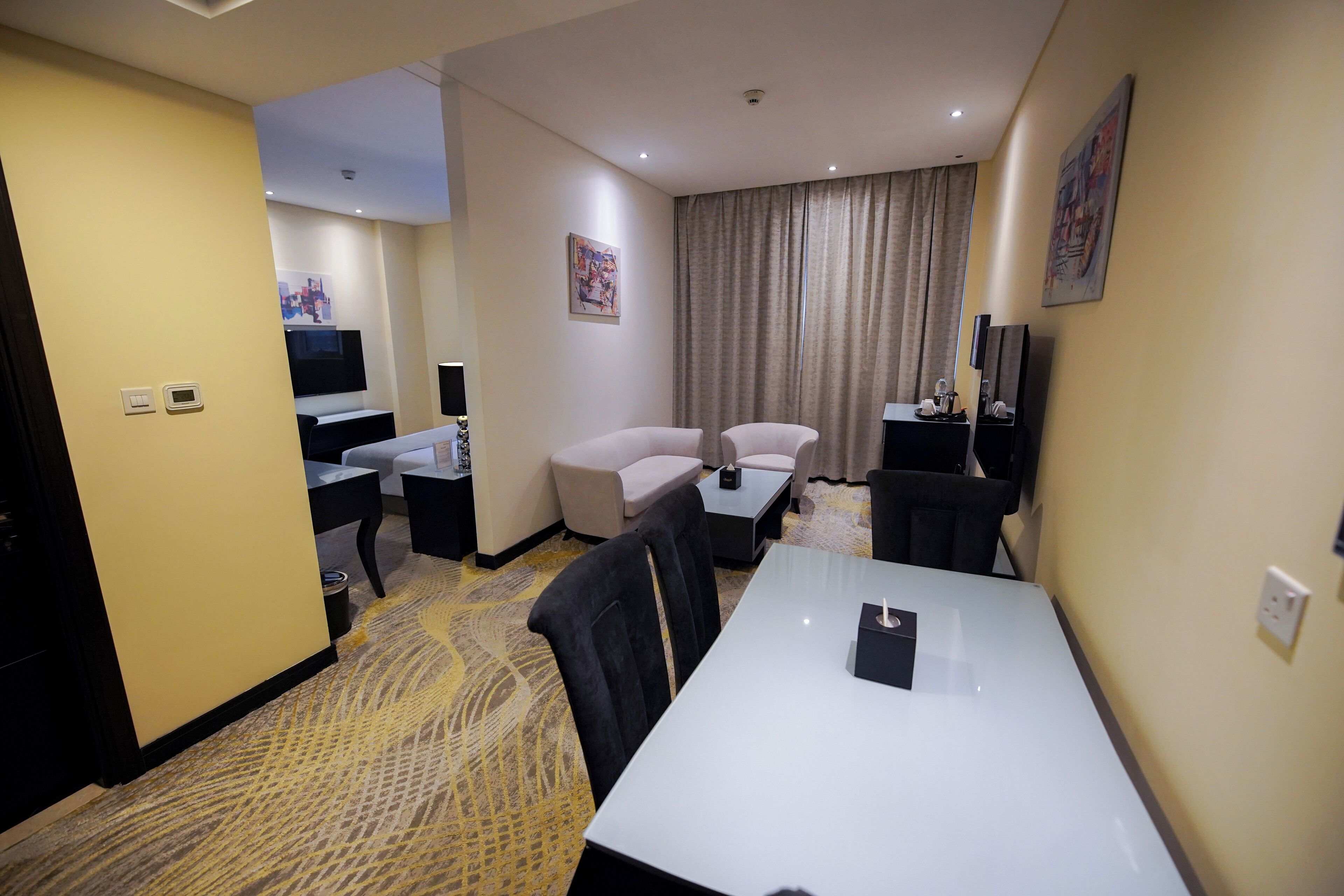Una habitación de hotel con cama, escritorio, sillón, televisión y un cuadro en la pared.