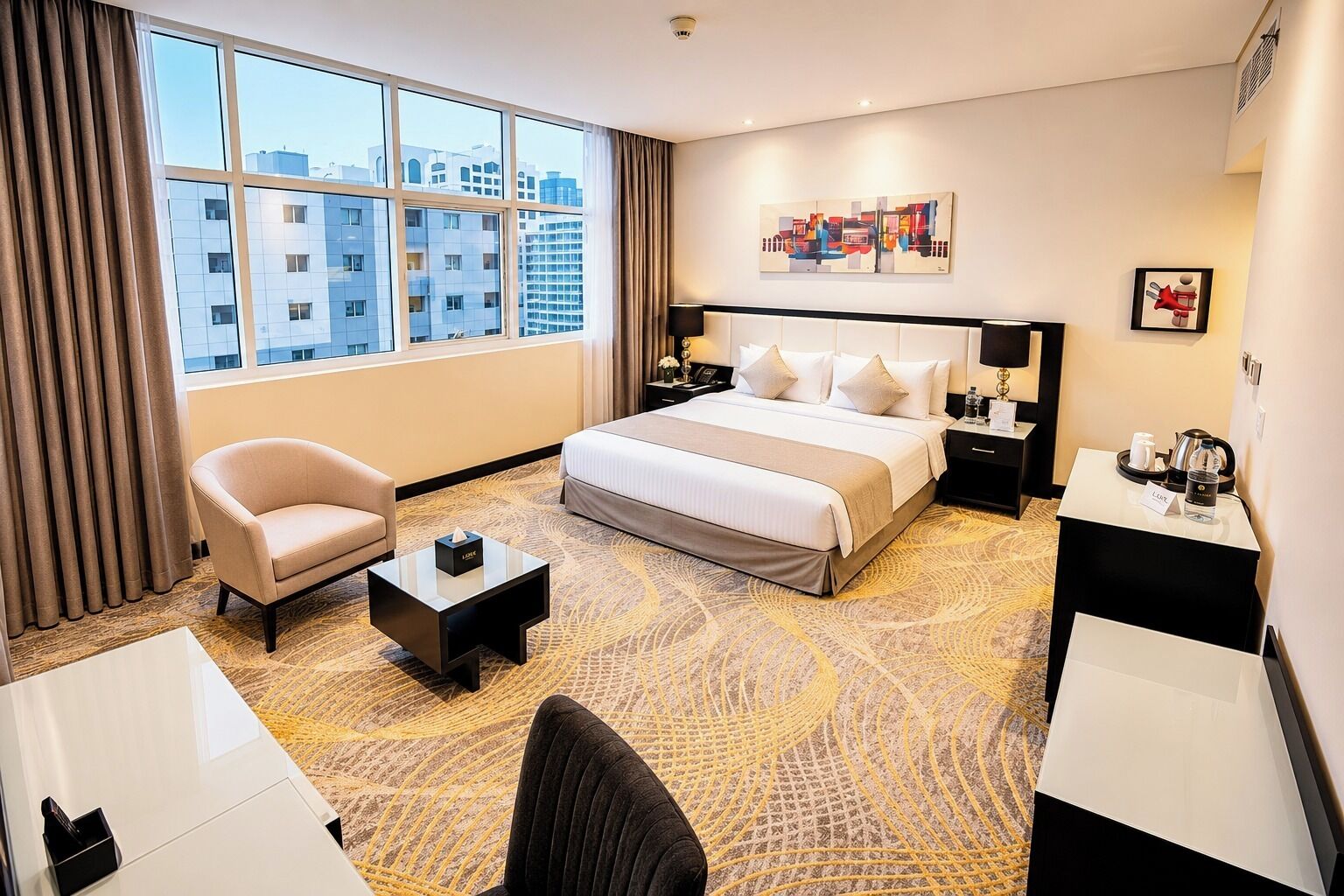 A hotel room with a large bed, a desk, a chair, a nightstand, a coffee table, and a view of the cityscape through the window.