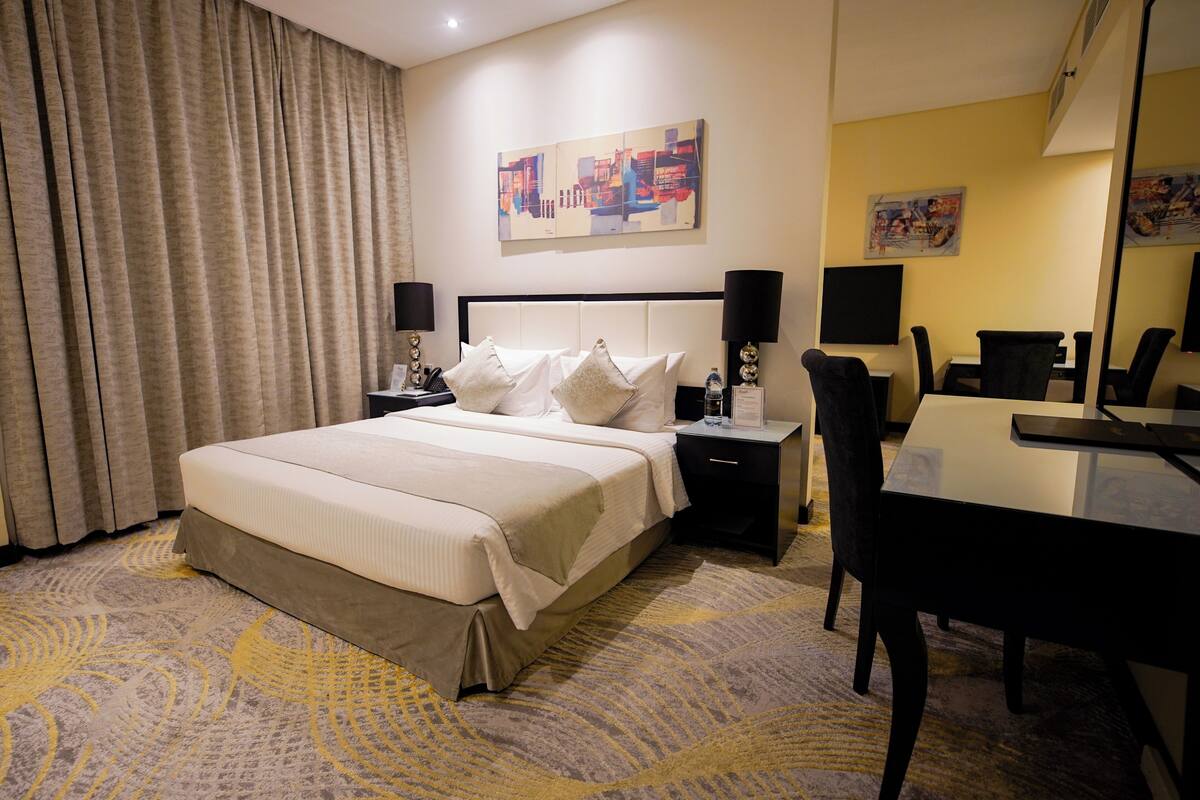 Ein Hotelzimmer mit einem großen Bett, Nachttischen, einem Schreibtisch und Stühlen.