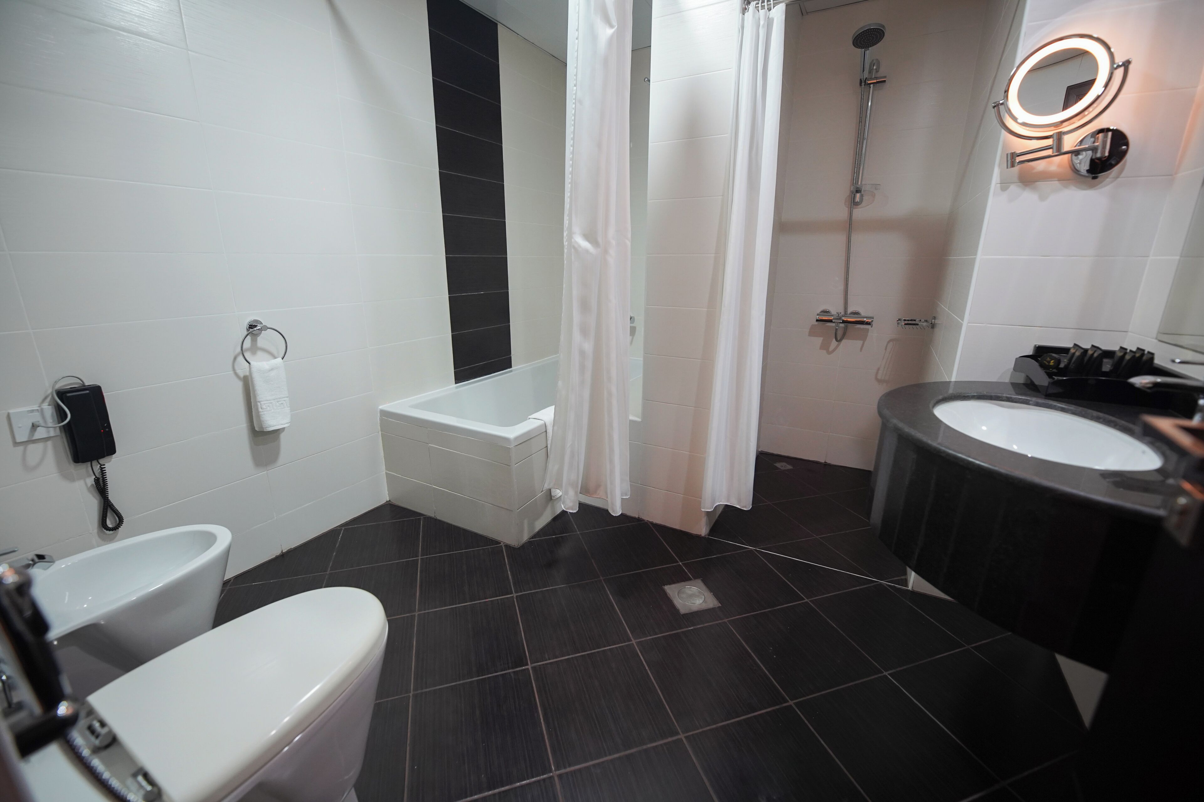 A bathroom with a toilet, bidet, bathtub, and a sink with a mirror.