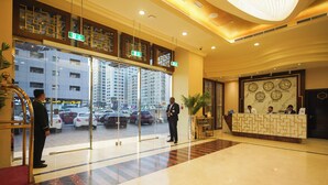 A hotel lobby with a reception desk, a large window overlooking a parking area, and a modern interior design. - Grand Villaggio Hotel Abu Dhabi (Abu Dhabi)