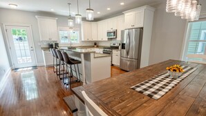 A modern kitchen with white cabinets, stainless steel appliances, and a wooden island with bar stools.