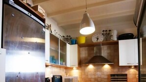 A compact kitchen with a stainless steel refrigerator, a microwave, a stove, and a sink. - Amati Villa Cavo Dellos (Mykonos)