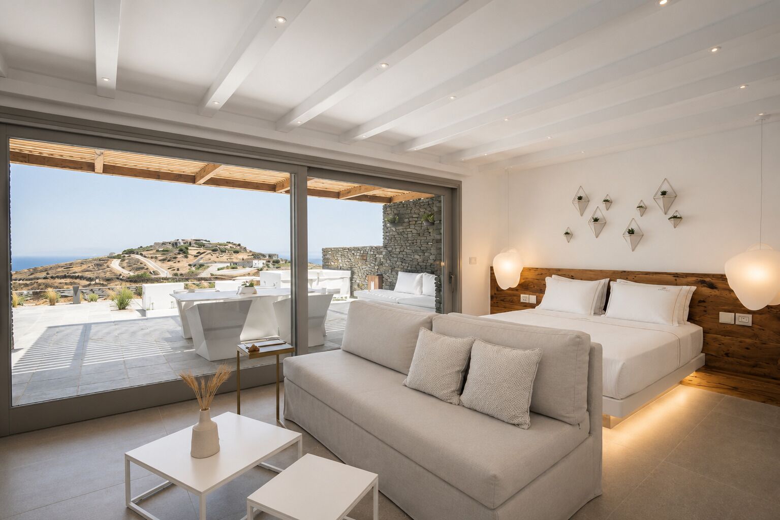 A modern bedroom with a large window, a sofa, a bed, and a view of the landscape.